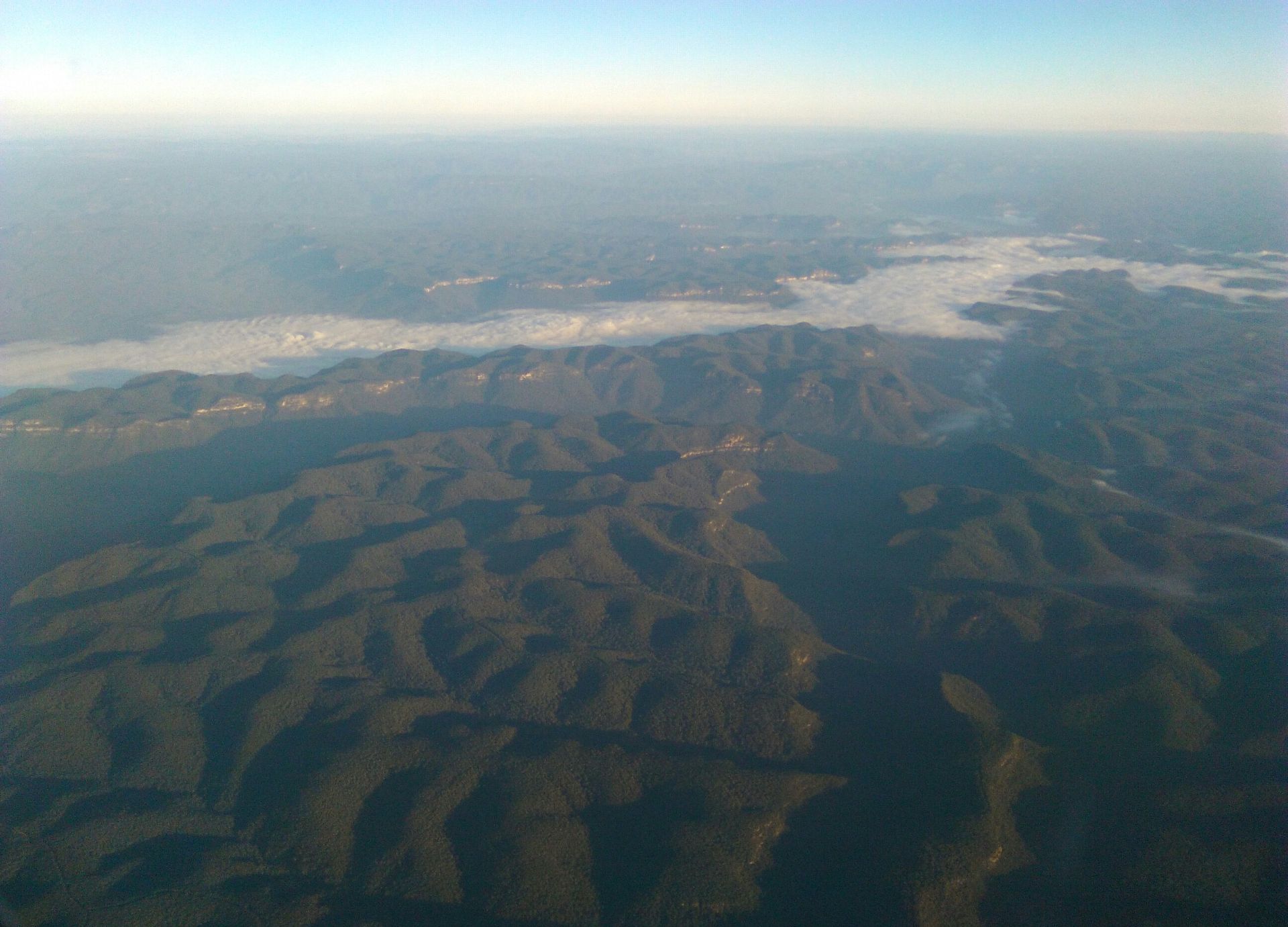 Aerial view of forested mountains with a river of cloud in the valleys