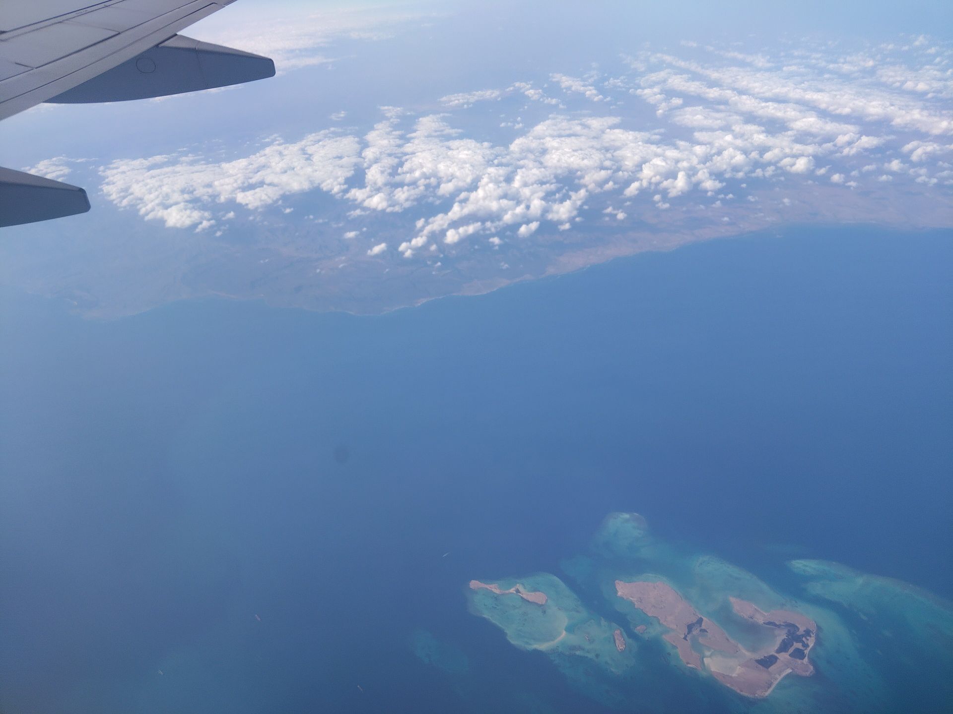 View from an aircraft window over a turquoise sea and small islands